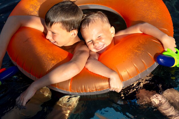 Jongens die plezier hebben bij het zwembad met dobber en waterpistool
