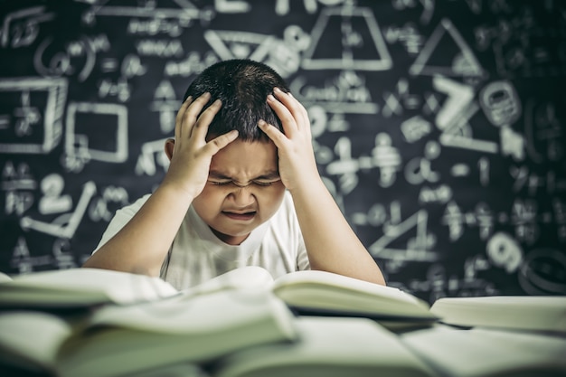 Jongens met een bril schrijven boeken en denken in de klas