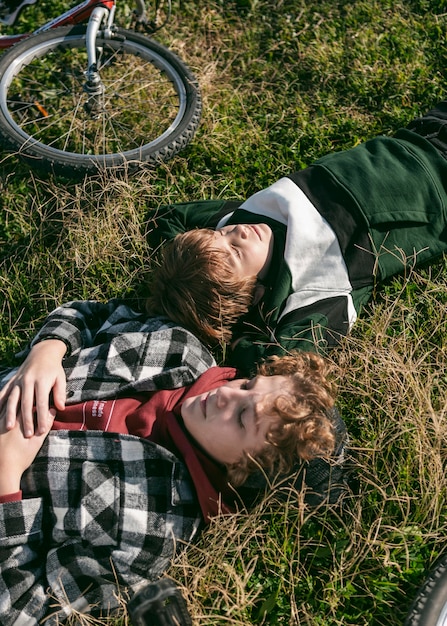 Gratis foto jongens rusten op gras terwijl ze fietsen