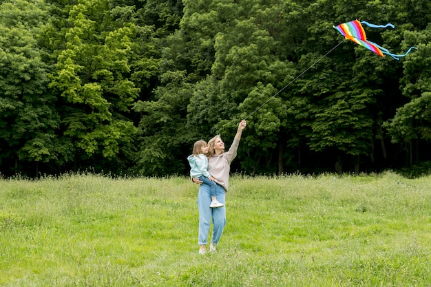 Jongere buitenshuis en moeder spelen met kite