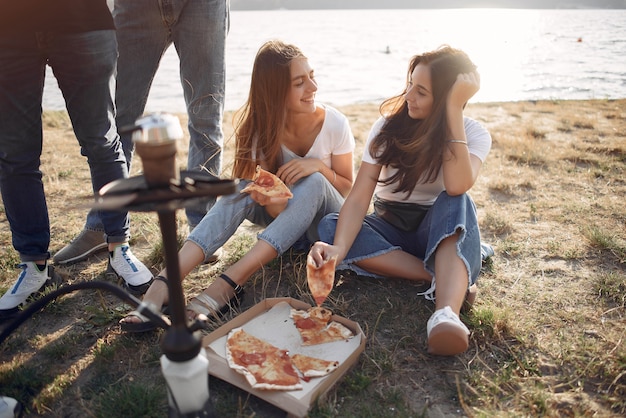 Jongeren die pizza eten en shisha roken bij het strand
