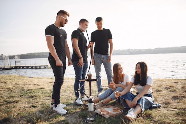 Jongeren die pizza eten en shisha roken bij het strand