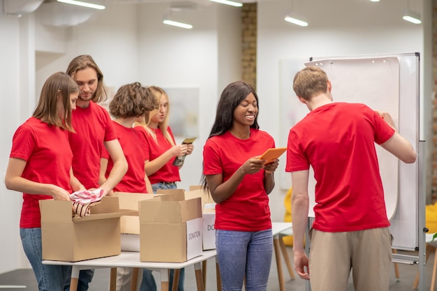 Jongeren in het rood zien er druk uit terwijl ze bezig zijn met het uitdelen van donaties