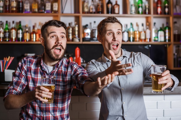 Jongeren met bier kijken naar voetbal in een bar