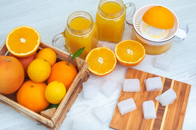 Jus d'orange met wat verse oranje ijsblokjes en sinaasappelpers bovenaanzicht