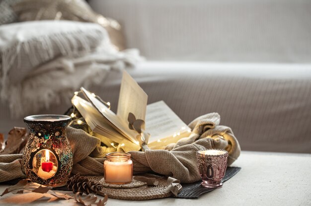 Kaarsen in kandelaars, boek, trui, slinger op de lichte ruimte van de woonkamer.