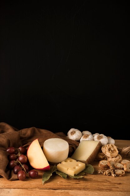 Kaas, druiven, knoflook en gezonde snack tegen zwarte achtergrond