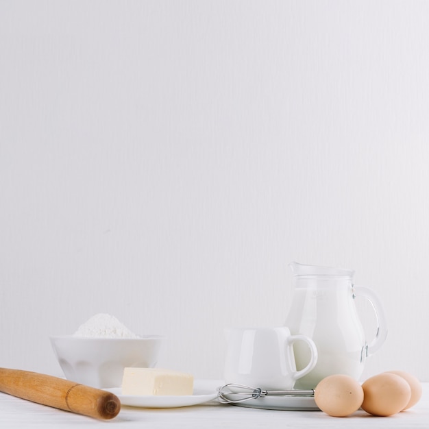 Kaas; meel; melk; deegroller; whisker en eieren op witte achtergrond voor het maken van taart
