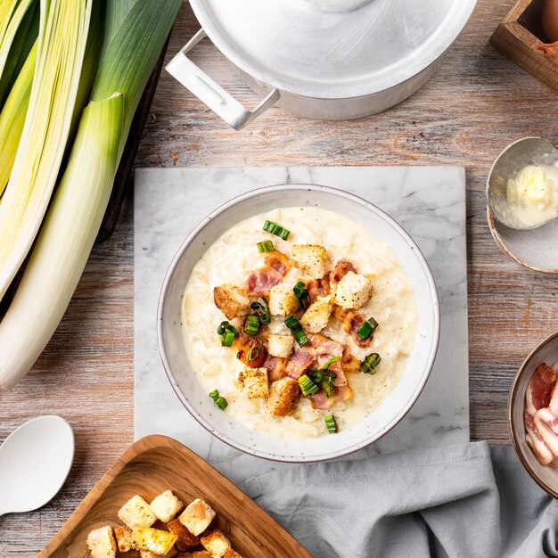 Kaas-preisoep met croutons en spek in een kom op een houten tafel