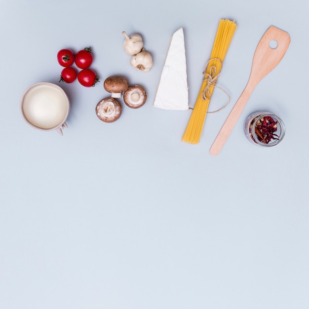 Kaas; verse groenten en witte saus voor het maken van spaghetti pasta&#39;s op een grijze ondergrond