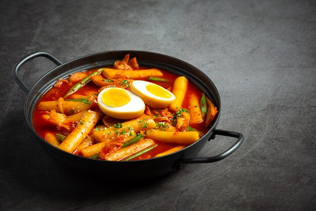 Kaasachtig Koreaans traditioneel voedsel Tokbokki op zwarte raadsachtergrond. Lunch gerecht.