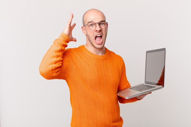 Kale man met computer schreeuwend met handen in de lucht, woedend, gefrustreerd, gestrest en overstuur