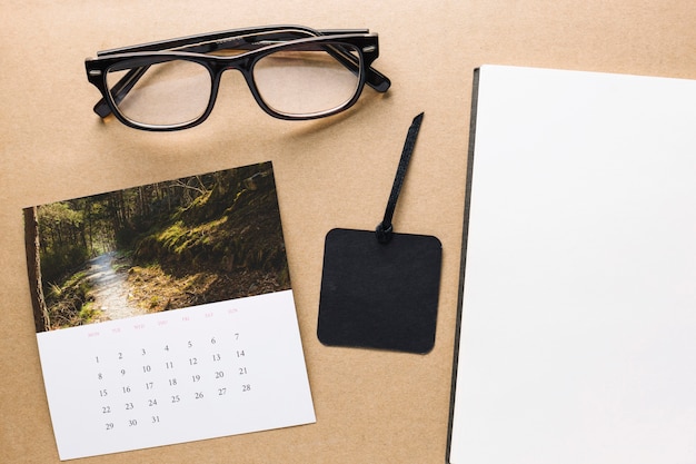 Kalender en glazen dichtbij notitieboekje