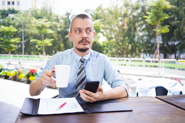 Gratis foto kalme peinzende zakenman met baard het drinken koffie