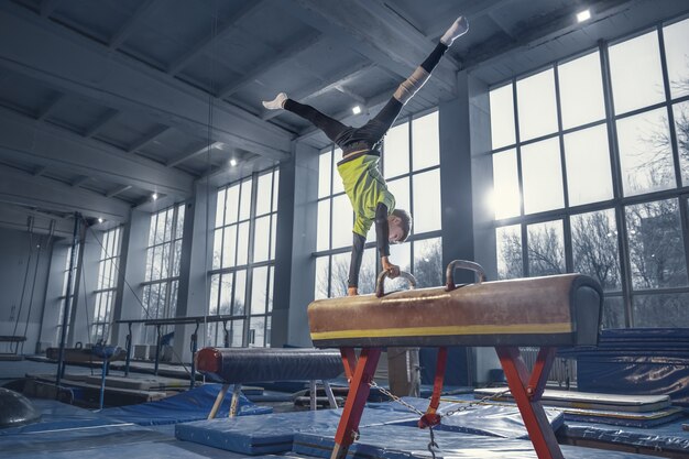 Kampioen. Kleine mannelijke turnster training in de sportschool, flexibel en actief