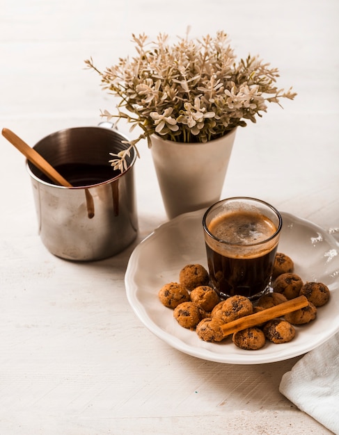 Kaneelstokjes op chocoladekoekjes met koffieglas en vaas