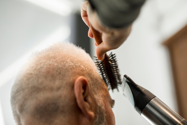 Gratis foto kapper die het stileren aan mannetje in salon maakt