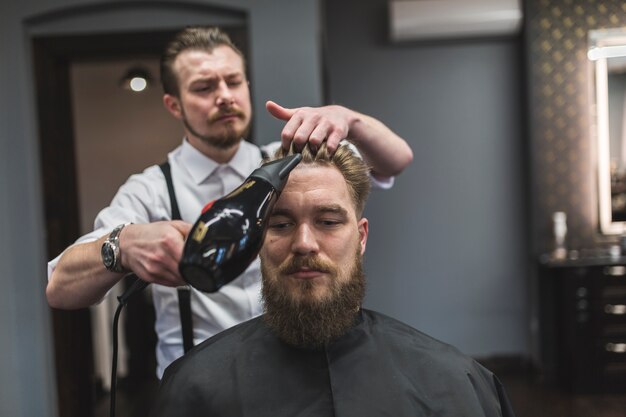 Kapper droog haar van de bebaarde man