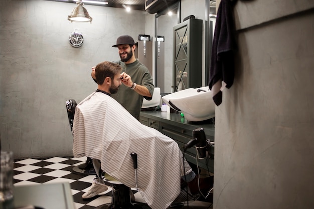 Gratis foto kapper knipt het haar van een klant in zijn winkel
