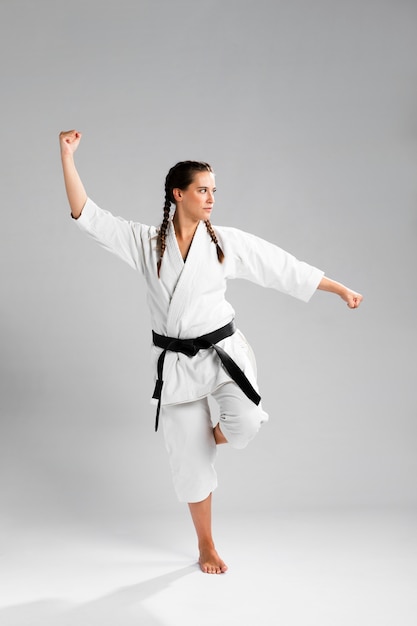 Karatevrouw in actie op witte achtergrond wordt geïsoleerd die