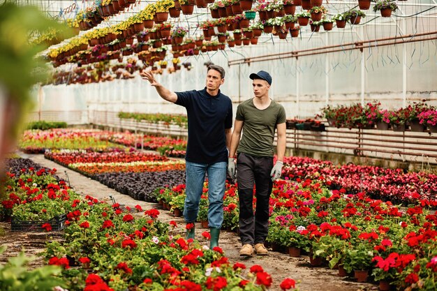 Kaseigenaar en zijn medewerker communiceren al wandelend en onderzoeken bloemen