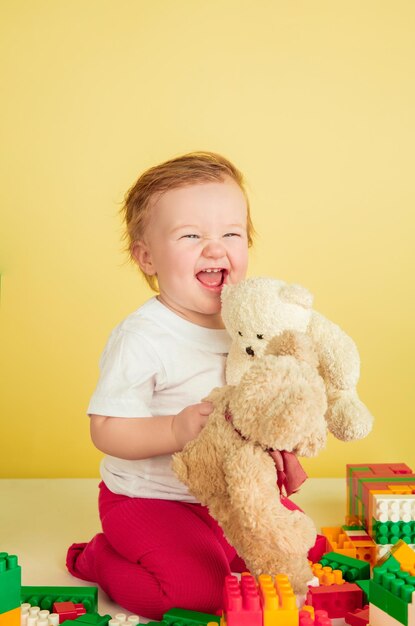 Kaukasisch meisje, kinderen geïsoleerd op gele studio achtergrond. Portret van schattig en schattig kind, baby spelen en lachen.