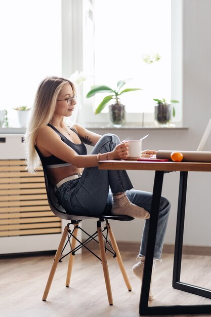 Kaukasische freelancer vrouw werkt vanuit huis. Vrouw houdt thee chatten of kijken naar film gebruik laptop.