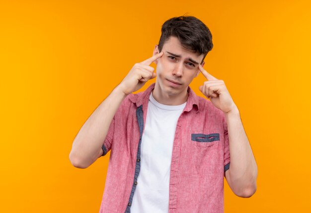 Kaukasische jonge man met roze shirt legde zijn vingers op de ogen op geïsoleerde oranje muur