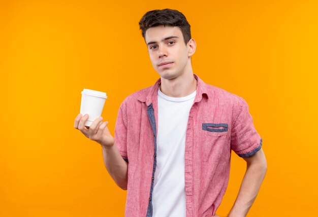 Kaukasische jonge man met roze shirt met kopje koffie op geïsoleerde oranje muur