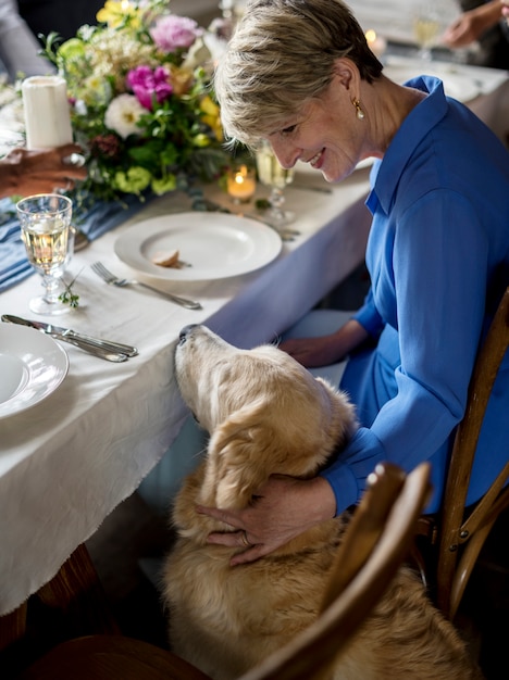 Kaukasische vrouw aaien Golden Retriever bij feestreceptie