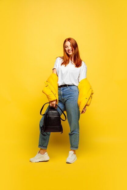 Kaukasische vrouw portret op gele achtergrond. Mooi vrouwelijk rood haarmodel.