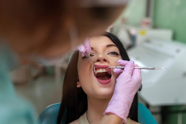 Kaukasische vrouwelijke arts onderzoekt de tanden van de patiënt met tandheelkundig instrument, gezondheids- en stomatologieconcept