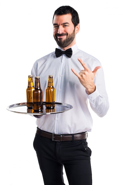 Kelner met bierflessen op de dienblad waardoor horing gebaar wordt gemaakt