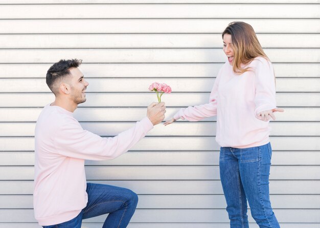 Kerel met bloemen dichtbij verraste dame