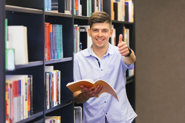 Kerel met boek die duim op gebaar maken