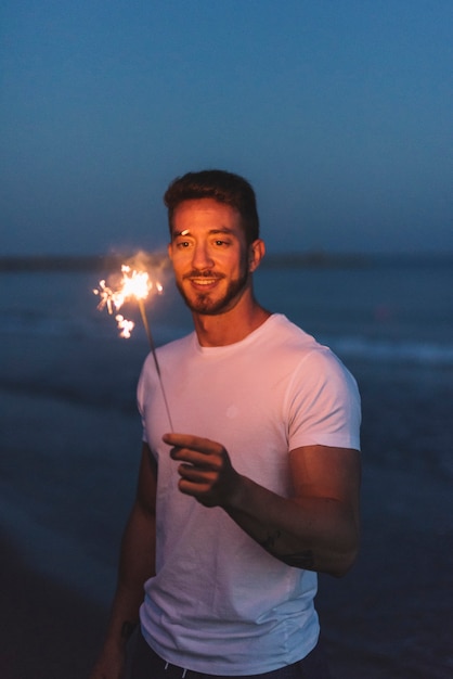 Kerel met sparkler op het strand