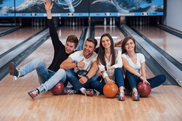 Kerel veel plezier met opgeheven armen. Jonge vrolijke vrienden vermaken zich in het weekend in de bowlingclub