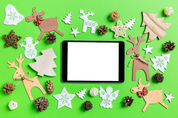 Kerst groene achtergrond met vakantie speelgoed en decoraties. bovenaanzicht van digitale tablet. gelukkig nieuwjaarsconcept.
