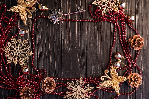 Kerst- of nieuwjaarsframe. Kersttakken, dennenappels en rode ketting op houten planken