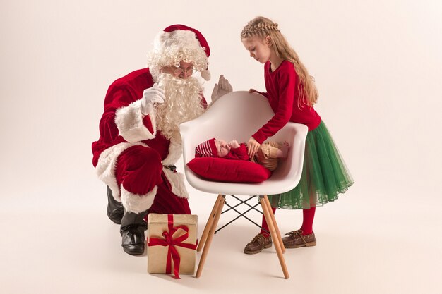 Kerst portret van schattig klein pasgeboren babymeisje, mooie tiener zus, gekleed in kerst kleding en kerstman met geschenkdoos