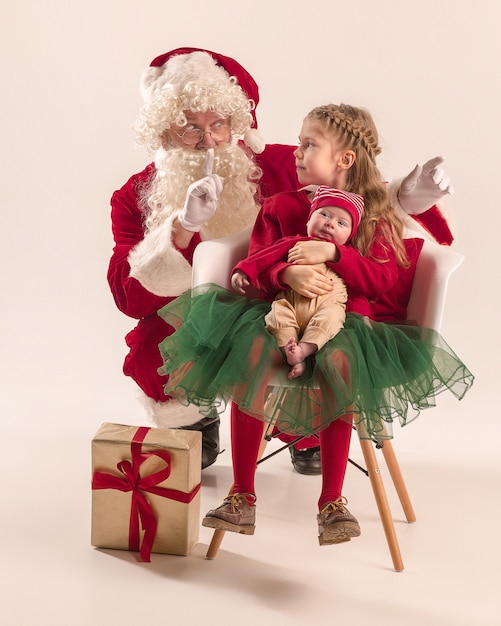 Kerst portret van schattig klein pasgeboren babymeisje, mooie tiener zus, gekleed in kerst kleding en kerstman met geschenkdoos