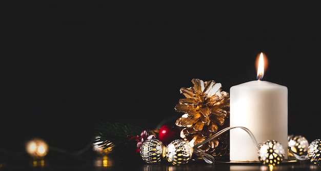 Kerst witte kaars met gouden dennenappel, mistletoe en lichte snaar gloeien