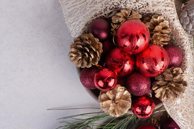 Kerstballen en dennenappel op witte tafel.