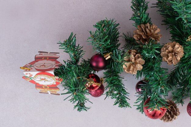 Kerstboom met rode ballen en dennenappels op grijze ondergrond
