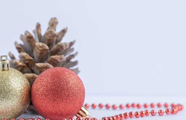 Kerstboomballen en eiken kegels met rode parelketting op het wit