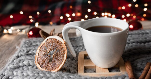 Kerstcompositie met een kopje thee, gedroogde sinaasappelen, kruiden op een onscherpe achtergrond.
