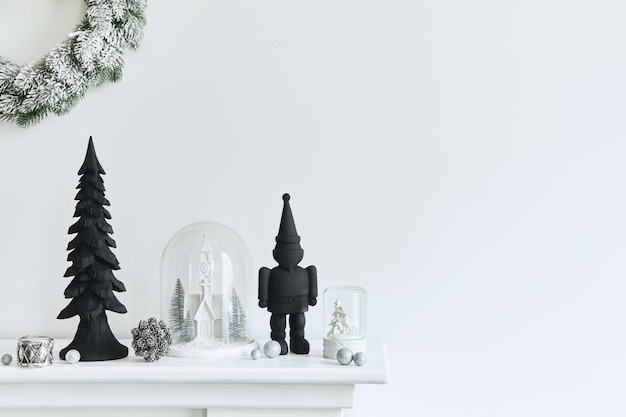 Kerstcompositie op de witte schoorsteen in het interieur van de woonkamer met prachtige decoratie. kerstboom en krans, kaarsen, sterren, licht. ruimte kopiëren. sjabloon.