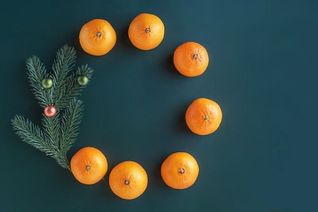 Kerstcompositie op een groene achtergrond. kerstboom met speelgoed en verse mandarijnen.