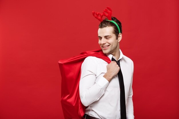 Kerstconcept Knappe zakenman viert prettige kerstdagen en gelukkig nieuwjaar, draag rendierhaarband met rode grote zak van de kerstman