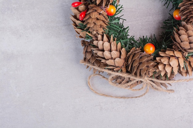 Gratis foto kerstkrans met rode kralen op witte tafel.